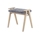 Sängpall med grå fårskinnsdyna och ljust trä med A-formade ben