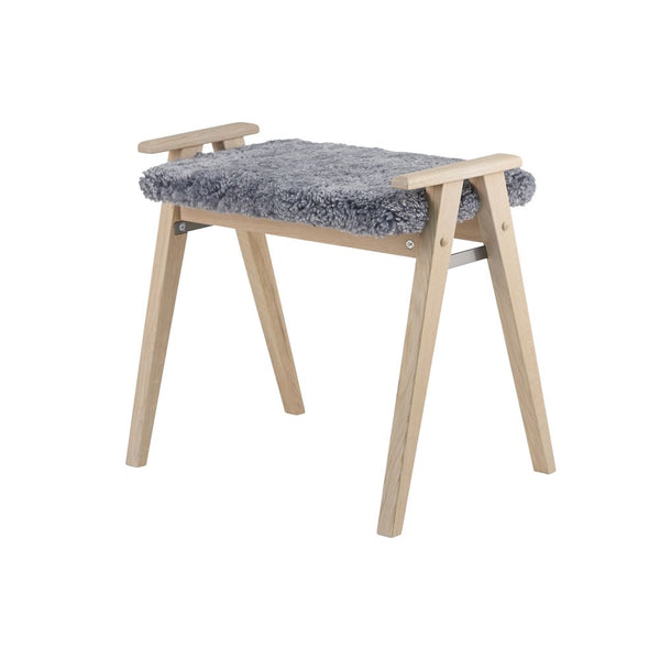 Sängpall med grå fårskinnsdyna och ljust trä med A-formade ben