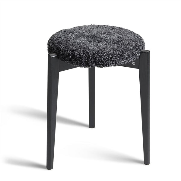 Rund pall med svart träram och grå fluffig sits i fårskinn