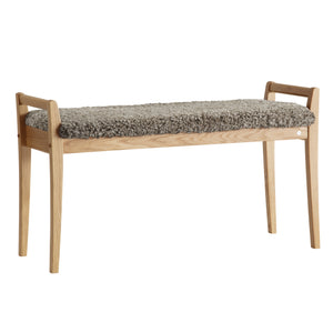 Bänk i ljust trä med fluffig grå fårskinnsdyna, skandinavisk design med raka ben och armstöd