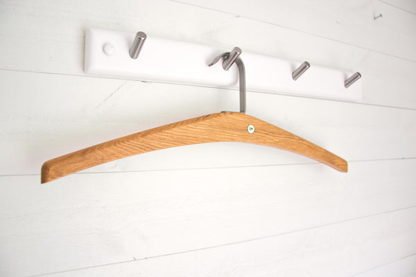 Träklädhängare i ek hängande på vit krokpanel med metallkrokar