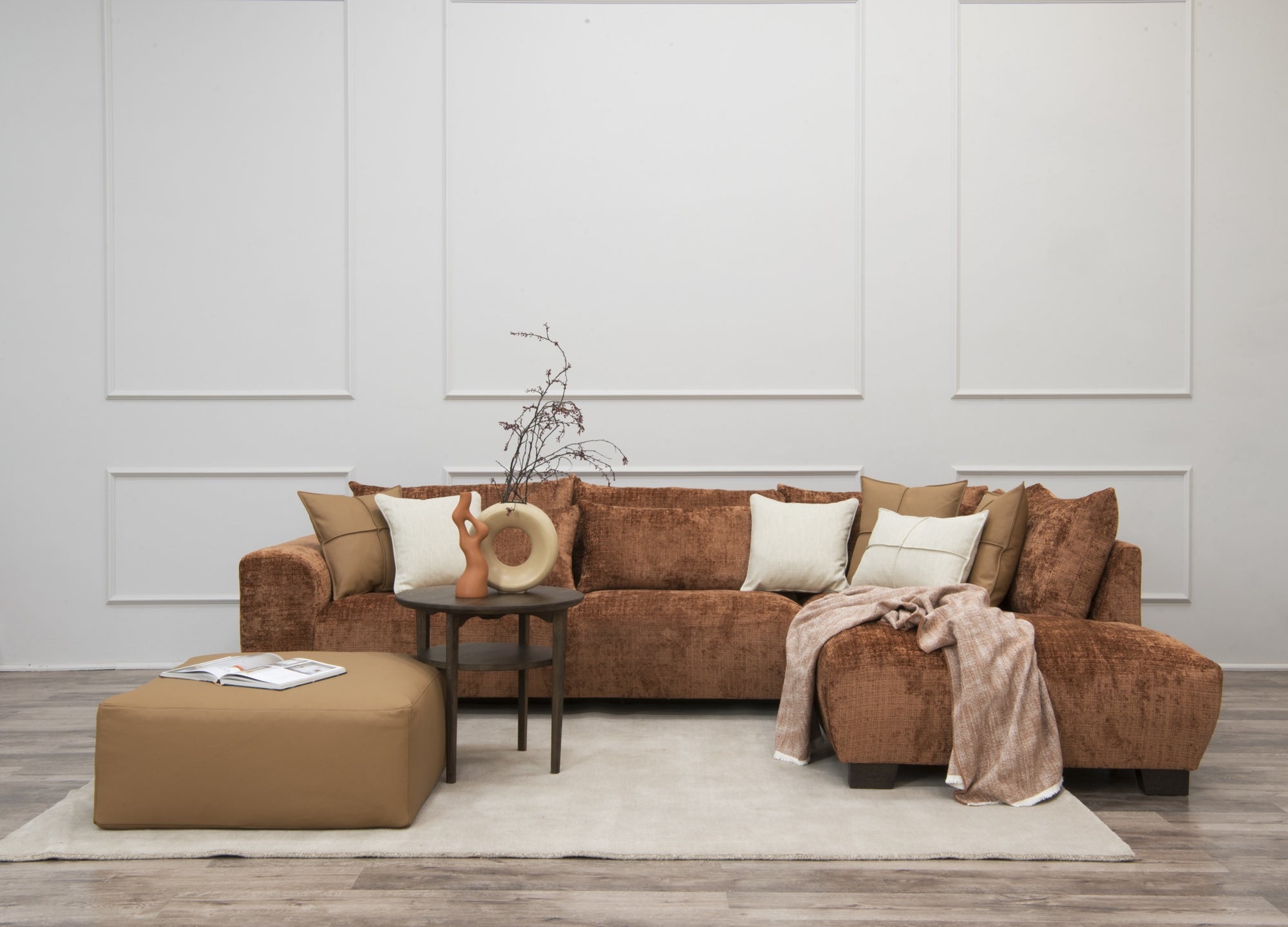 Brun schäslong soffa med kuddar och pläd i moderna vardagsrum med beige och vita toner