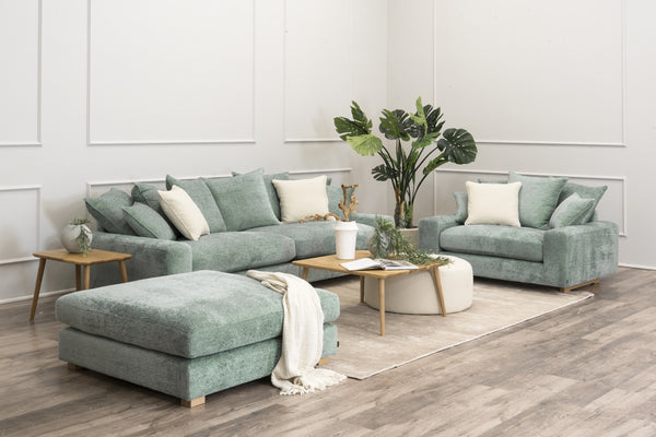 Turkos soffa, fåtölj och pall med beiga kuddar i modernt vardagsrum med trägolv och växtdekor