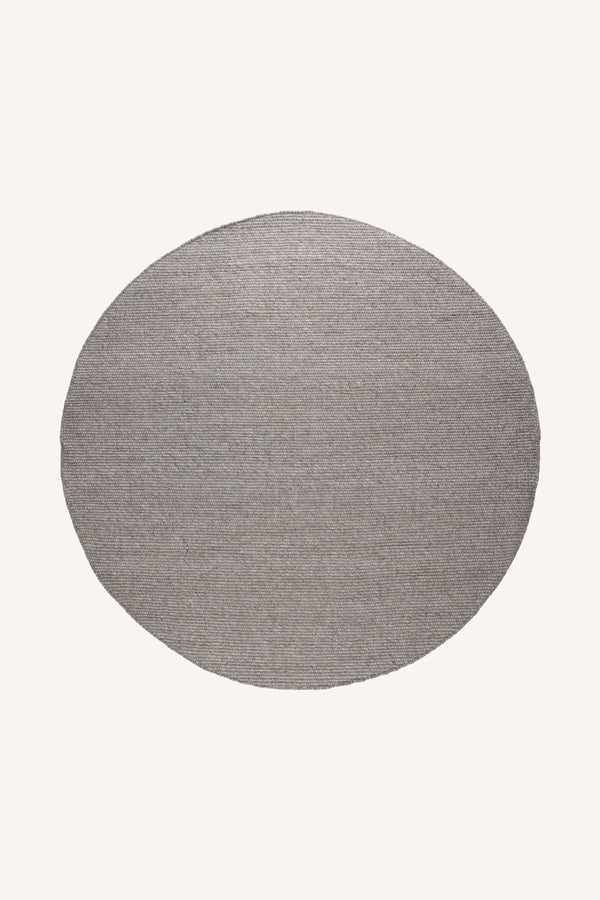Rund grå matta med texturerad yta på ljus bakgrund