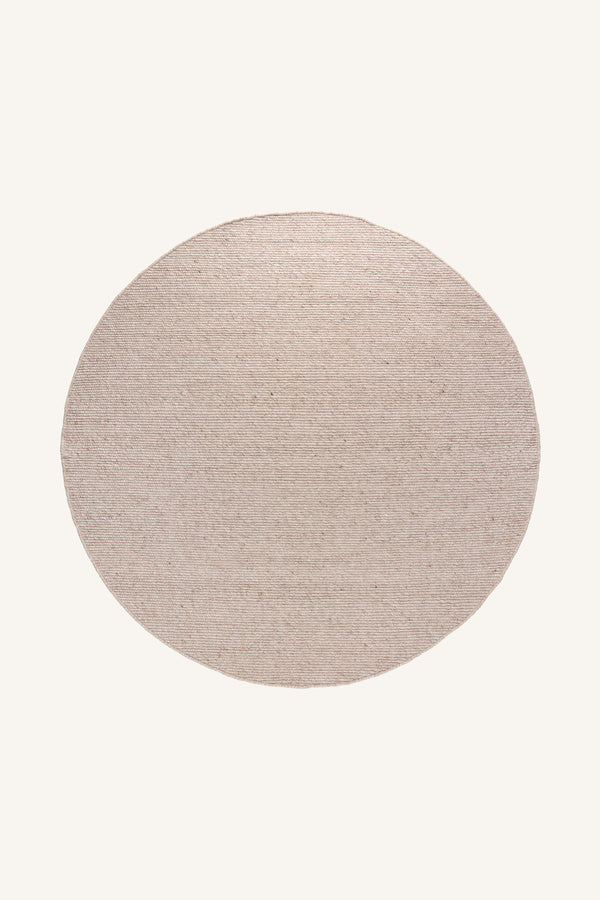 Rund beige jutematta med naturlig textur ovanifrån på ljus bakgrund