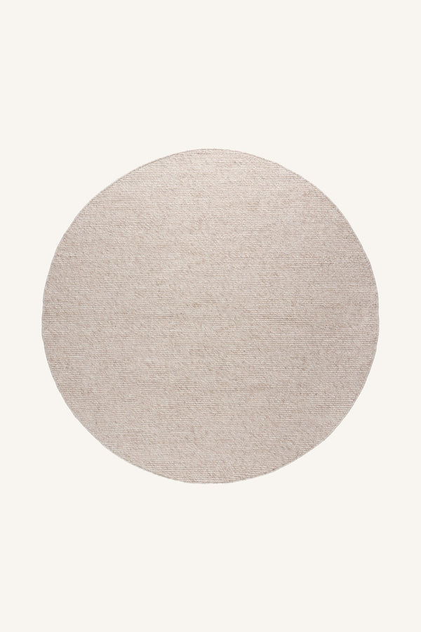 Rund matta i ljusbeige färg med naturlig textur, ovanifrån fotograferad mot ljus bakgrund