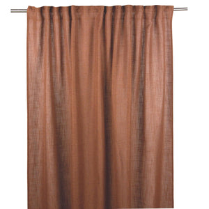 Terrakottafärgad gardin i linne hängande på gardinstång med veck och naturlig struktur