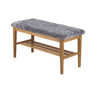 Bänk med grå fårskinnsdyna och ekram med hylla för förvaring av skor
