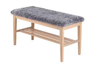 Bänk med grå fårskinnsdyna och ljust trästativ med hylla för förvaring