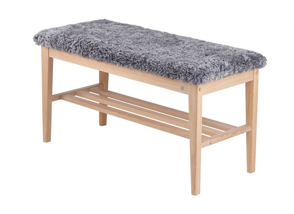 Bänk med grå fårskinnsdyna och ljust trästativ med hylla för förvaring