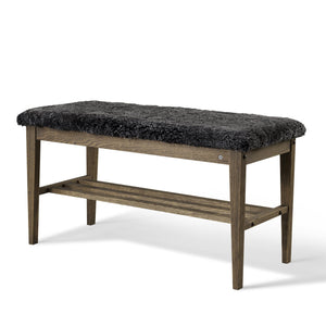 Hallbänk med grå fårskinnsdyna och trästomme i mörkt trä med hylla