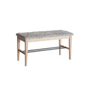 Hallbänk med grå fårskinnsdyna och ljust trästativ med hylla för skoförvaring