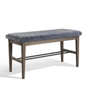 Hallbänk med grå fårskinnsdyna och mörkbrunt trästomme med skoförvaring i metall