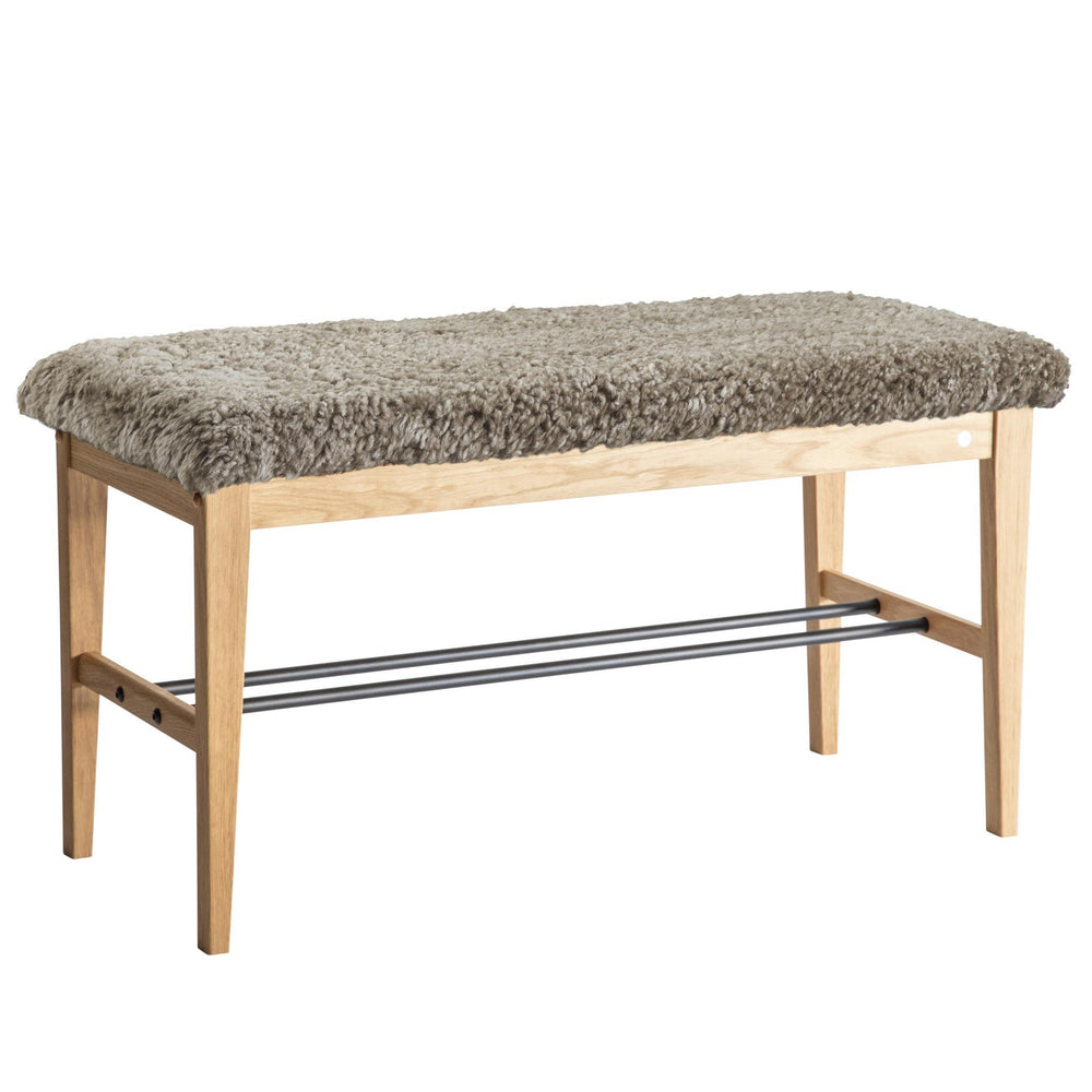 Bänk med grå fårskinnsdyna och ljust trästomme med metallhylla för skoförvaring