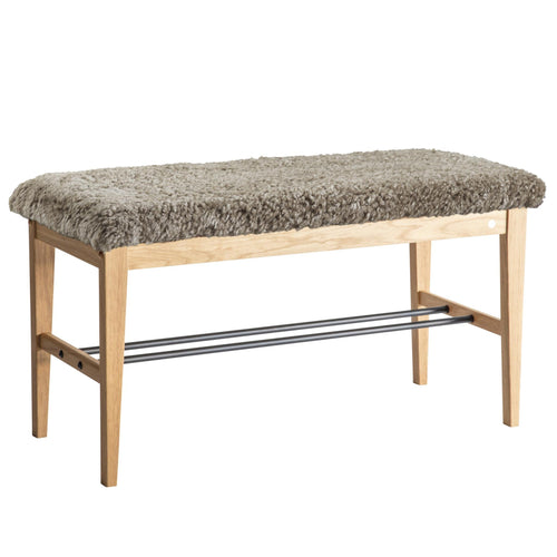Bänk med grå fårskinnsdyna och ljust trästomme med metallhylla för skoförvaring