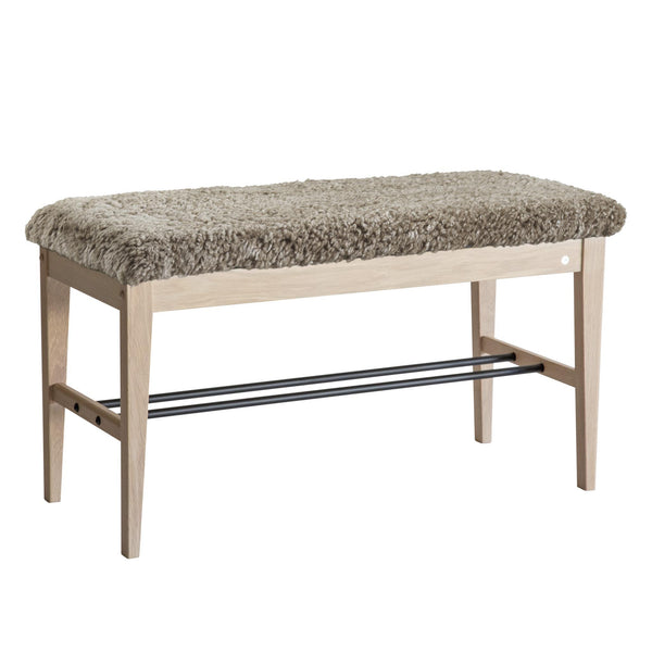 Hallbänk i ljust trä med grå fårskinnsdyna och svart skoställning under sittdynan