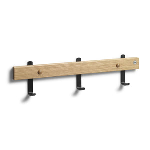 Väggkroklist i ek med tre svarta krokar och två träknoppar för förvaring av kläder och accessoarer