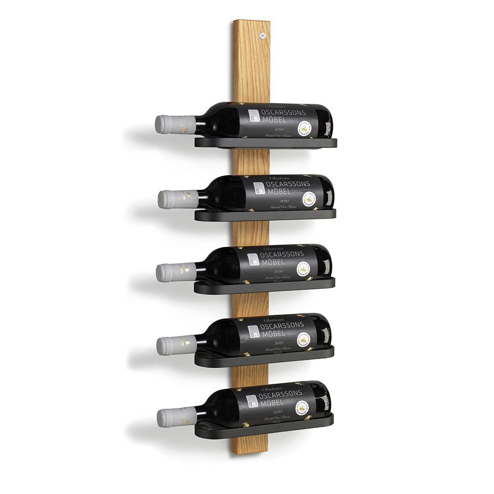 Vinställ i trä med fem svarta hyllplan som håller vinflaskor i vertikal montering mot vit vägg