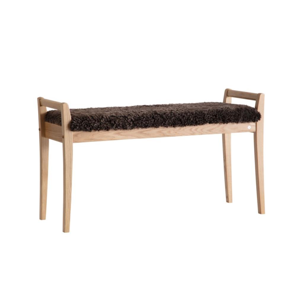 Bänk i ljust trä med mörk fårskinnsdyna, skandinavisk design med smala ben och armstöd