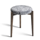 Pall med grå fuskpäls och mörka träben i skandinavisk design