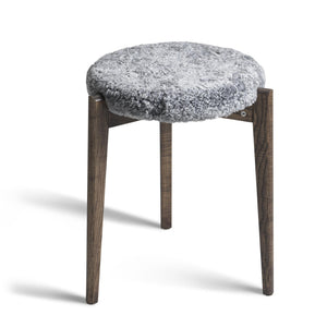 Pall med grå fuskpäls och mörka träben i skandinavisk design