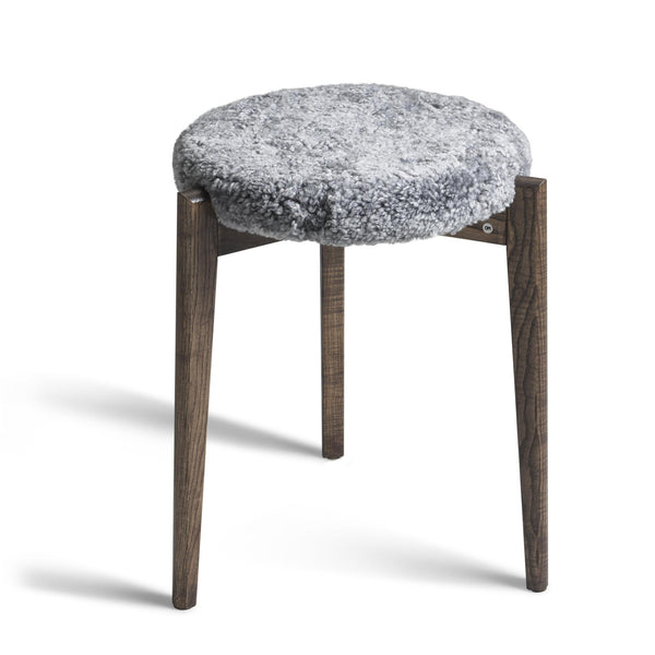 Pall med grå fuskpäls och mörka träben i skandinavisk design