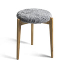 Pall med grå fårskinnsdyna och ben i ljust trä, rund design