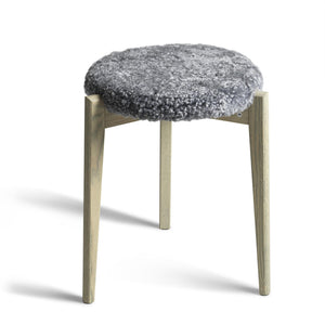 Pall med grå ullig sits och ljusa träben i modern skandinavisk design