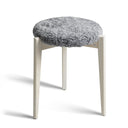 Pall med grå fårskinnsdyna och vitlaserade träben i skandinavisk design