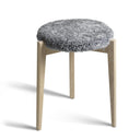 Pall med grå fårskinnsdyna och ben i ljust trä