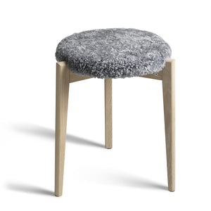 Pall med grå fårskinnsdyna och ben i ljust trä