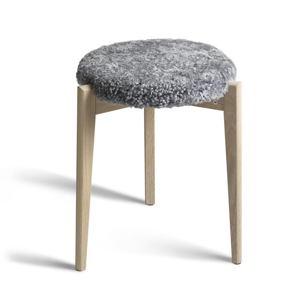 Pall med grå fårskinnsdyna och ben i ljust trä