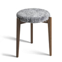 Pall med grå fårskinnsdyna och ben i mörkt trä