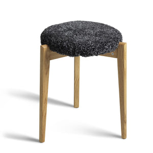 Pall med naturlig ekram och mörkgrå fårskinnsdyna, modern skandinavisk design