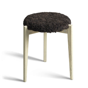 Rund pall med mörkt fårskinn och ljusa träben i skandinavisk design