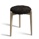 Rund pall med svart fårskinnsdyna och ljusa träben i ek