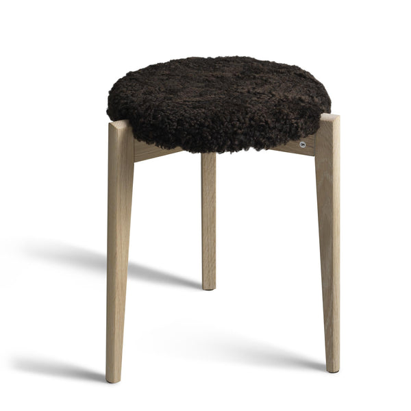 Rund pall med svart fårskinnsdyna och ljusa träben i ek