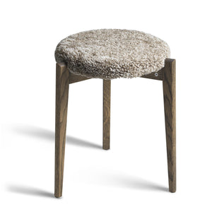 Rund pall med grå fårskinnsdyna och mörkbruna träben i modern skandinavisk design