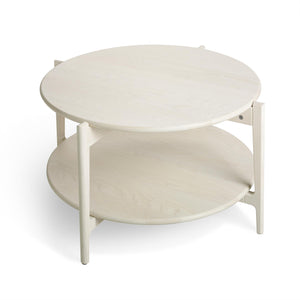 Runt soffbord i ljust trä med två hyllplan och vitlackerade ben i skandinavisk design