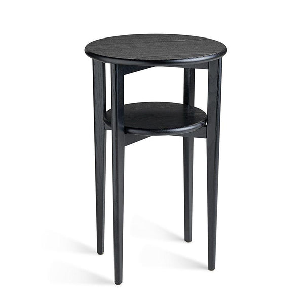 Runt svart sidobord i trä med två våningsplan och fyra ben mot vit bakgrund