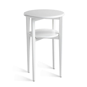 Vitt runt sidobord med två våningar och smala metallben, minimalistisk design