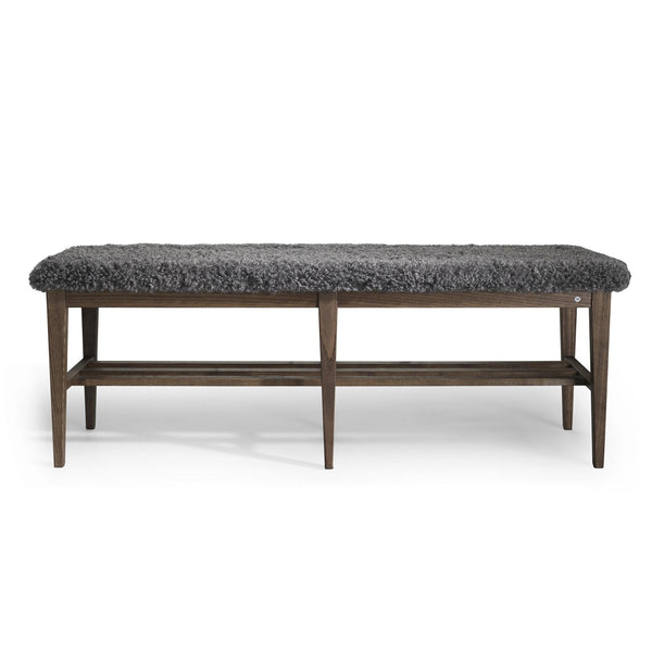 Bänk med grå fårskinnsdyna och mörkbrunt trästativ med hyllplan