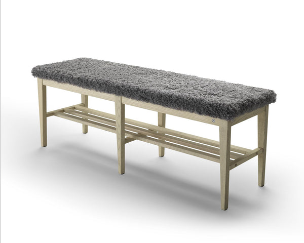 Bänk med grå fårskinnsdyna och ljust trästativ med hylla för förvaring av skor