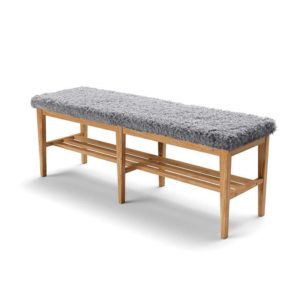 Hallbänk med grå fårskinnsdyna och träunderrede med skohylla