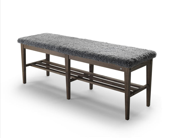 Bänk med grå pälsliknande sits och mörkt trästomme med hyllplan för skoförvaring