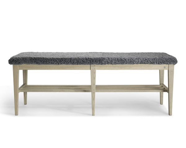 Hallbänk med grå fårskinnsdyna och ljust trästativ med förvaring, modern skandinavisk design