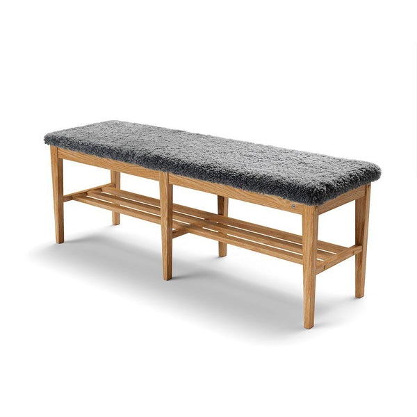 Hallbänk i ek med grå fårskinnsdyna och förvaring under sitsen