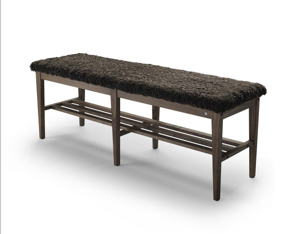 Smal hallbänk med mörkgrå fårskinnsdyna och träram med förvaring under sittdynan