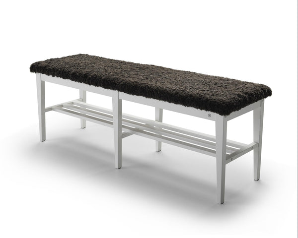 Hallbänk med svart fårskinnsdyna och vit metallstomme med skoförvaring under sitsen