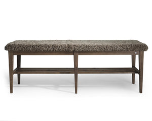 Bänk med grå fårskinnsdyna och mörkt träunderrede med hylla